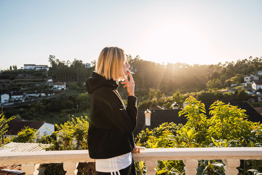 blonde woman smoking a cigarette on a gazebo against sunset