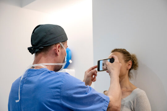 Aesthetic surgeon taking photograph of patient before operation