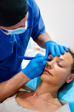 Surgeon drawing line on girl eye with marker preparing for procedure.
