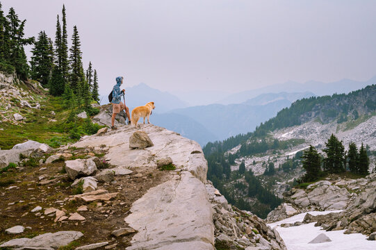 Male hiker and dog standing on a cliff in the north cascades