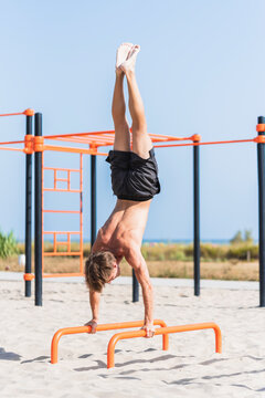 Young man practicing calisthenics on parallel bars.