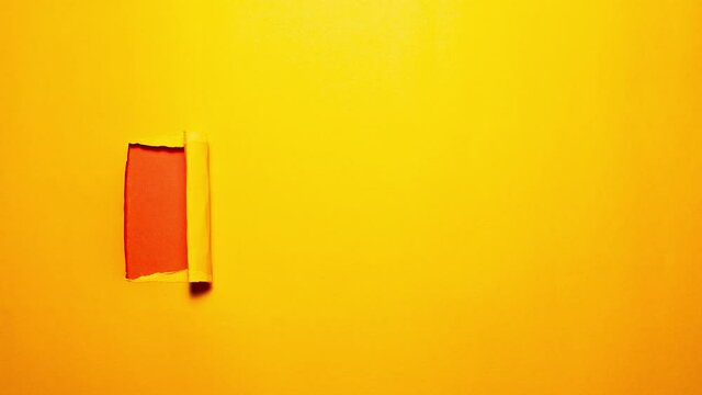 Stop motion photography concept. Diagonally torn orange paper on red.