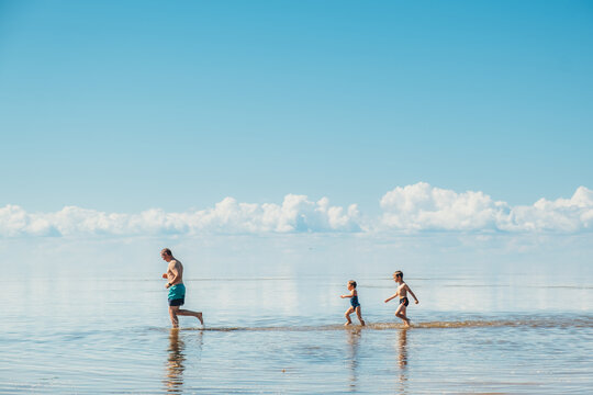 Father and children running and playing on the lake at the day time.