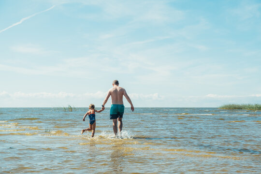 Father and daughter swimming on the lake at the day time.