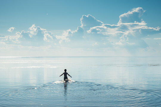 The boy swimming on the lake. Theme of summer outdoor activities.