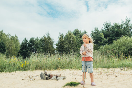 The cute girl spending time on the shore of the beautiful lake.
