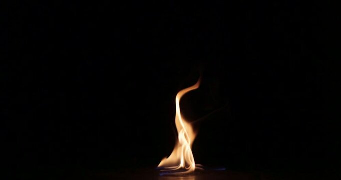 A single flame on a black background.