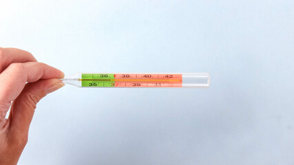 A mercury thermometer for measuring temperature turns on a blue surface.