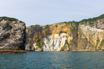 Fototapeta na wymiar Cliffs of the steep coast of the Pacific Ocean in Kamchatka, interesting geological structures of the cliff.