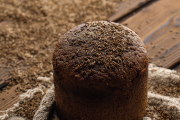 Round loaf of rye bread with thyme on rustic style wooden table