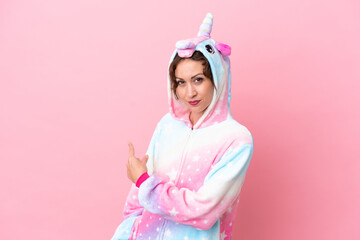 Young caucasian woman with unicorn pajamas isolated on pink background pointing back