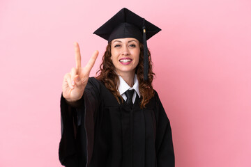Young university graduate woman isolated on pink background smiling and showing victory sign
