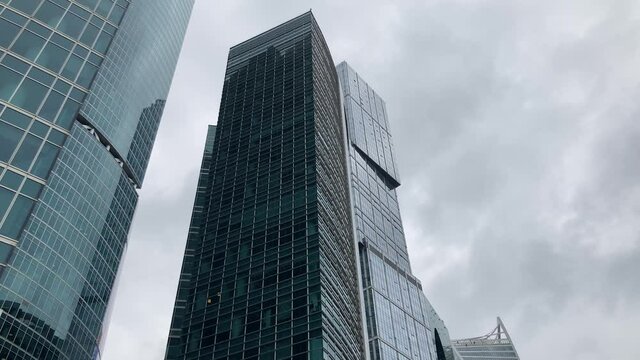 Facade of modern skyscraper with glass walls. From below of contemporary tall skyscraper with glass walls against cloudy sky in downtown
