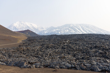 Kamchatka rocks from volcanic rocks multi-colored volcanic rocks. Crumbling volcano craters. against the backdrop of volcanoes with peaks in the snow and clouds. Ostry Tolbachik and Plosky Tolbachik.