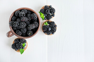 Blackberries and tartlets with blackberries top view on a wooden background with a place for an inscription. Blackberries and desserts with them