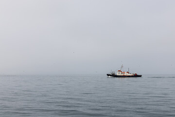 A lonely little ship sails along the calm,  foggy and misty Pacific Ocean in the Kamchatka