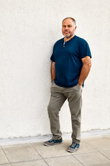 Portrait of a casually dressed middle aged man in front of a light gray urban wall with copy space.