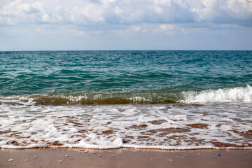 view from the beach, there are waves in the sea.