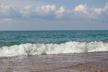 view from the beach, there are waves in the sea.