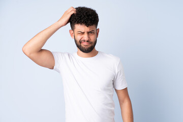 Fototapeta premium Young Moroccan man isolated on blue background having doubts while scratching head