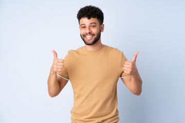 Young Moroccan man isolated on blue background giving a thumbs up gesture