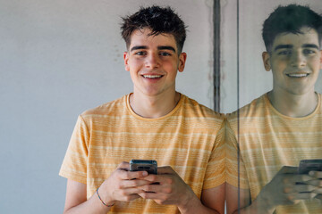 teenager with mobile phone leaning with reflection and copy space