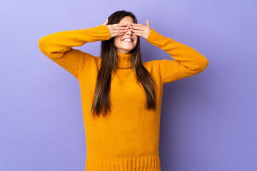 Teenager Brazilian girl over isolated purple background covering eyes by hands and smiling