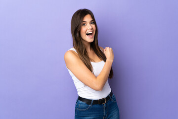 Teenager Brazilian girl over isolated purple background celebrating a victory