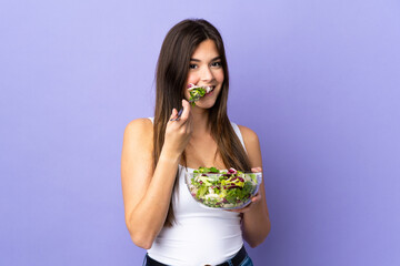 Teenager Brazilian girl holding a salad over isolated purple background