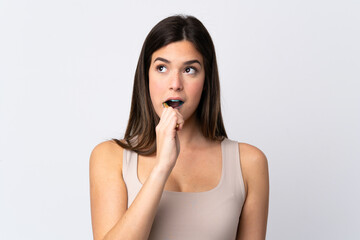 Teenager Brazilian girl brushing her teeth over isolated white background