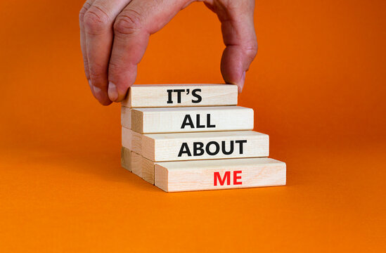 It is all about me symbol. Wooden blocks with words 'It is all about me'. Beautiful orange background. Businessman hand. Copy space. Business and it is all about me concept.