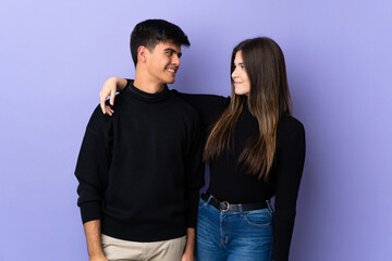 Young couple over isolated purple background happy and laughing