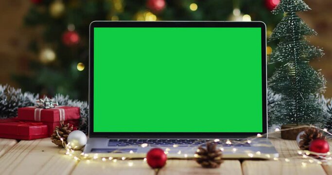 Laptop with green screen on screen, with christmas decorations and tree