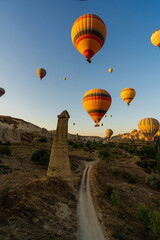 Vertical image of bunch of colorful hot air balloon flying early morning in Cappadocia, Turkey against typical rock formation due to volcanic activity in love valley located in Goreme national park