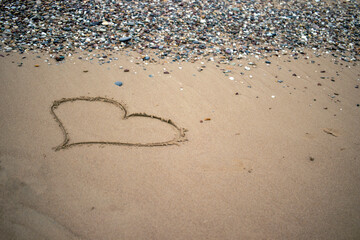 The heart symbol on the beach is drawn on the yellow sands of the shore. Valentine's Day.