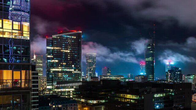 Time lapse night in Warsaw, Poland. Business center, skyscrapers, residential apartments and office buildings covered with clouds. Evening cityscape, high angle panoramic view central part of city