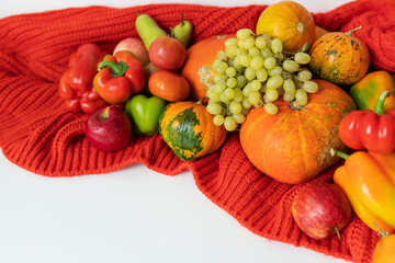 Thanksgiving Day. Big autumn harvest - pear, apples, pumpkin, pepper, tomato on a white background and red cloth. Thanksgiving celebration concept.