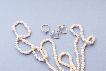 Natural pearl beads, earrings and ring on blue background. Wedding accessories for the bride