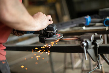 A man is working on a part in the garage.Metal grinding. Steel processing with power tools.