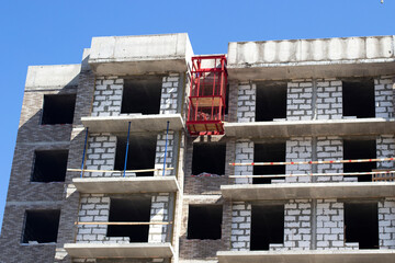 Construction of the building. Unfinished windows. The roof of a high-rise building. Bare brick block.