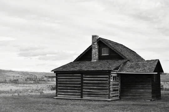 A black and white image of an old abandoned log house on the Alberta prairies. 