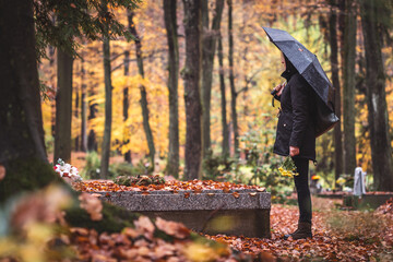 Silent grief in graveyard. Lone sad woman mourning for dead person at grave in cemetery. Mourner...