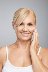 An attractive blond senior woman putting anti-age creme. Beauty photography