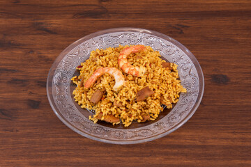 Glass plate with a portion of pastoret rice paella with prawns and squid in a Spanish tapas restaurant