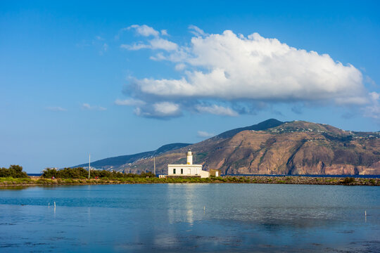 Salina island (Aeolian archipelago), Messina, Sicily, Italy, 08.17.2021: view of the salt lake with the white lighthouse in the background in Punta Lingua.