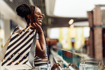 Young African American woman, with shopping bags walking in the mall