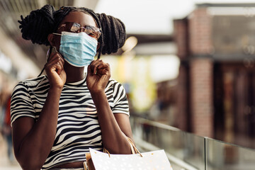 African American woman in protective medical mask, after shopping, shopping during the coronavirus pandemic