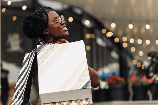 Beautiful African woman, in the mall with shopping bags, happy woman doing Christmas shopping
