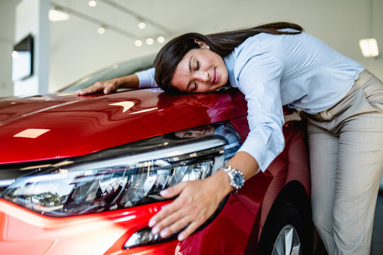 Beautiful woman buying a new car at the car showroom.