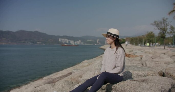 Woman sit on the rock and look at the sea